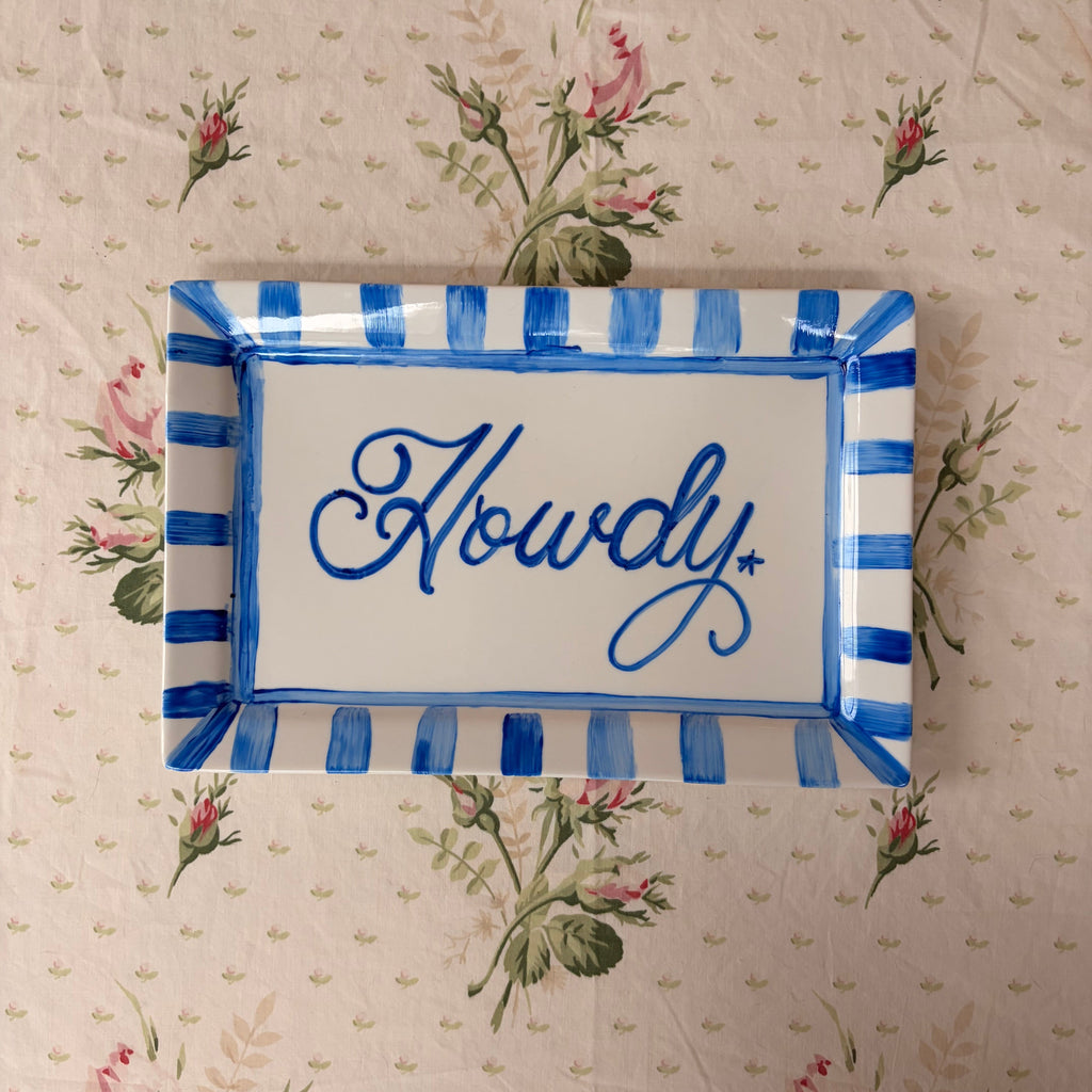 Hand painted blue Howdy text with a tiny star framed in a blue painted thick tripe border on a large white rectangle shaped platter