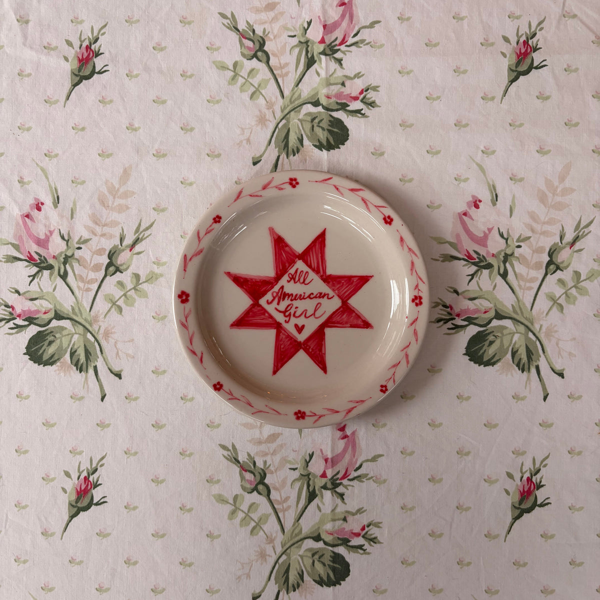 All American Girl cursive handwriting painted inside a red quilt block and framed with a dainty floral border