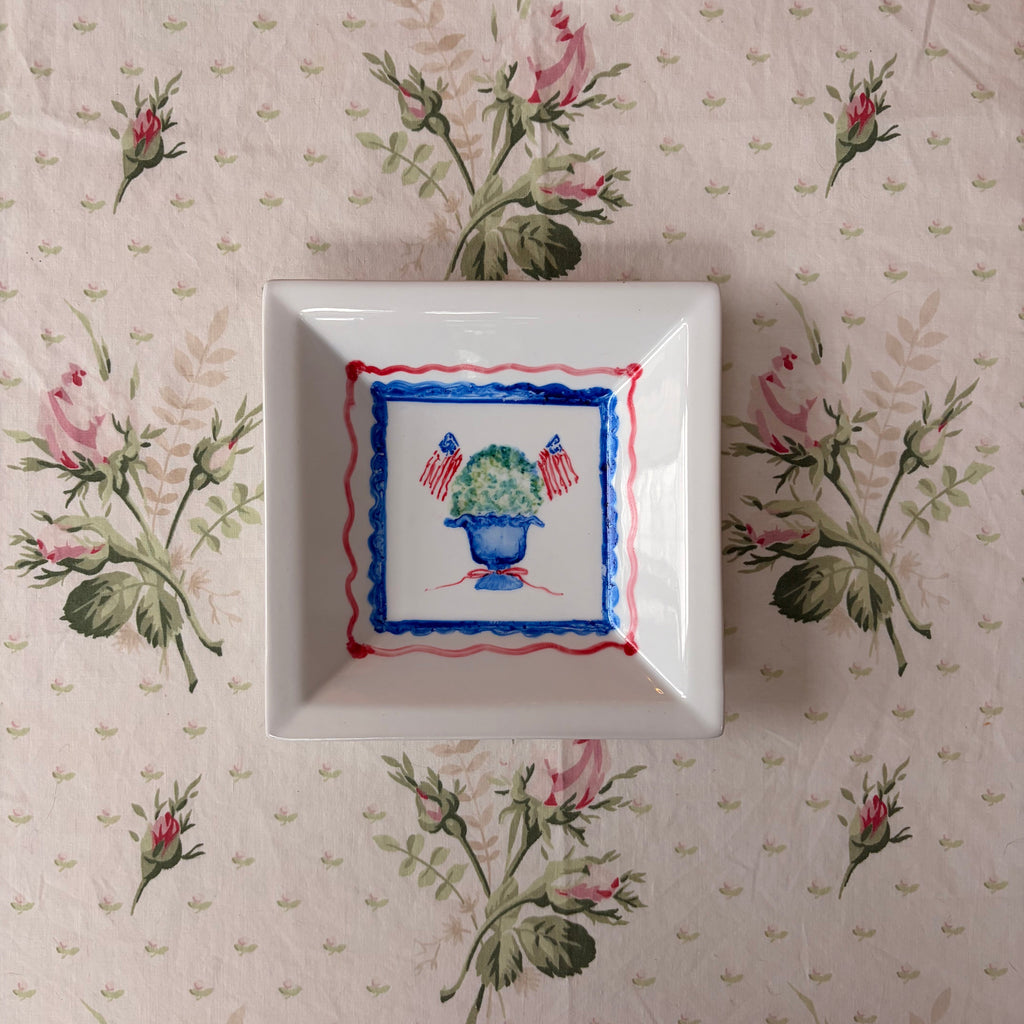 small square dish with hand painted green blue topiary with American flags framed in wavy red and blue scalloped frames