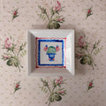 small square dish with hand painted green blue topiary with American flags framed in wavy red and blue scalloped frames